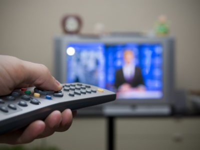 Person holds TV remote in front of television